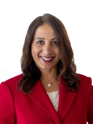 Dr. Nimmi Kappor smiling in red blazer headshot on white background