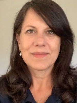 Headshot of a smiling woman with shoulder-length dark hair and pearl earrings