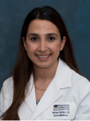 A woman with long black hair, wearing a resident physician's coat