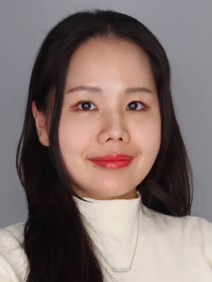 Headshot of a smiling woman wearing a white turtleneck on a gray background