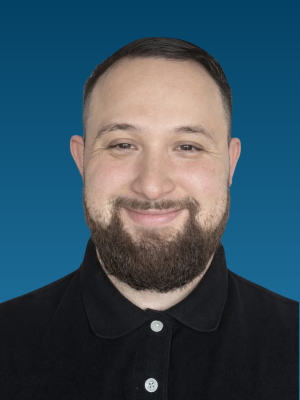 Smiling bearded man wearing black polo against teal gradient background.