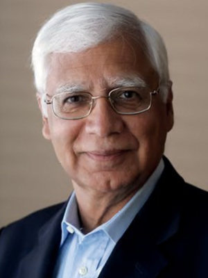 Deepak Chopra with white hair wearing a dark blazer and light blue shirt.