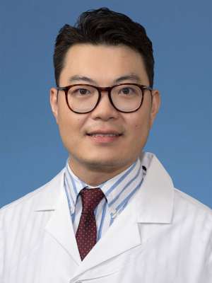 Head shot of Xioming Qi in white lab coat, smiling at camera