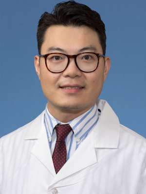 Head shot of Xioming Qi in white lab coat, smiling at camera
