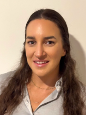 Hannah Jones with long brown hair wearing a light gray shirt, smiling against a plain background.