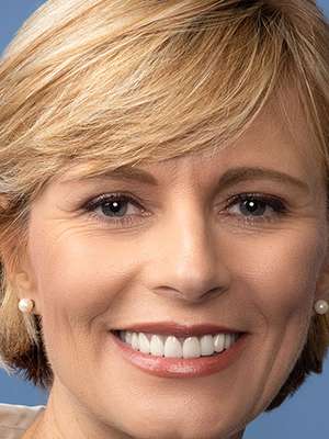 Headshot of an unidentified female professional against blue background.