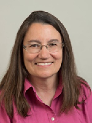 Head-and-shoulders portrait of a person with brown hair wearing a pink shirt