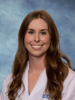 headshot of Dr. Adrienne Leigh in front of a blue background, wearing a lab coat