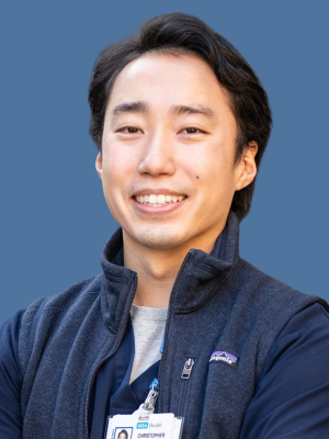 An Asian Male Nurse smiling where his UCLA badge.