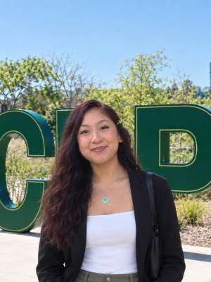 Woman smiling on campus in front of large green letter sculptures