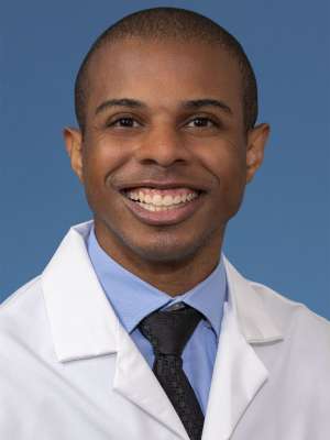 Head shot of Paul Lewis, MD, MS in white coat, smiling at camera