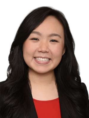 Smiling woman with long dark hair wearing a red top and black blazer