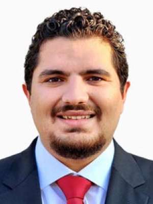 Ghanem Ghadi, smiling headshot in suit and red tie.