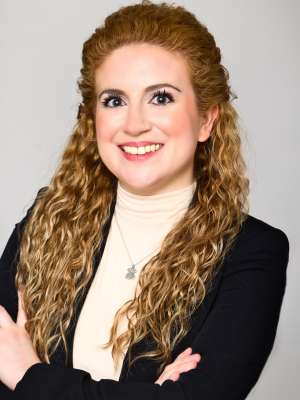 Headshot for Catherine Donat in front of a gray background in an indoor setting