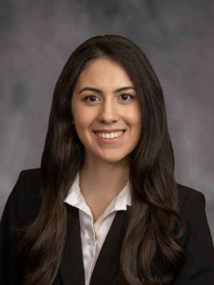 A woman with brown hair, wearing a blazer with a white shirt