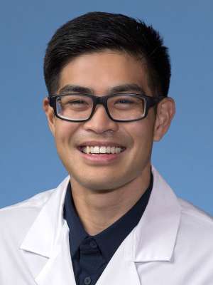 Joel Raqueno, DO in a white lab coat