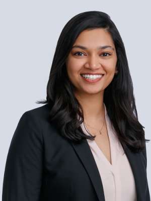A woman with black hair, wearing a light pink shirt with a suit jacket