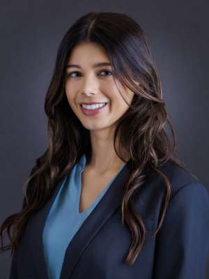 Emery Dutta headshot, wearing a light blue shirt and dark blue coat.