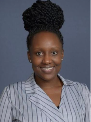 Headshot of a person with braided hair, wearing a striped shirt against a gray background.