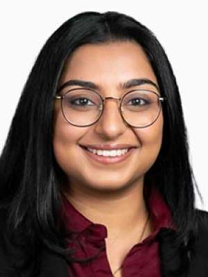 Nikita Nangia headshot, smiling woman wearing glasses and a blazer