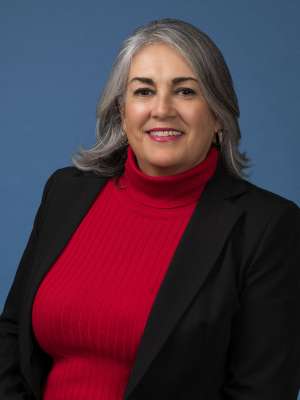 headshot of Aida Alvarez in black blazer and red turtle neck sweater