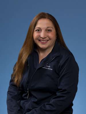 Termeh Toufanian with long hair wearing a navy jacket, sitting against a blue background.