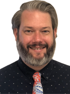 Bear Waters with salt-and-pepper beard wearing dark dotted shirt and colorful tie