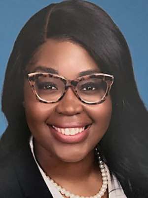 Smiling woman in professional headshot wearing tortoiseshell glasses and pearl necklace