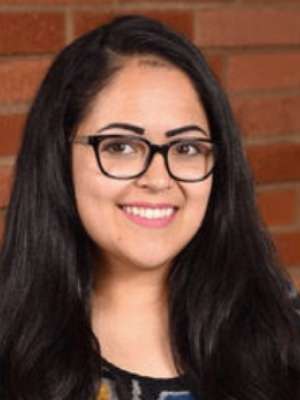 Headshot of Norma Sandoval with red brick wall in the background