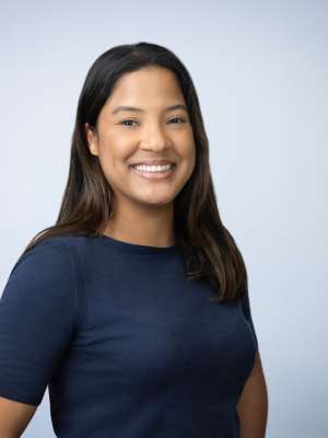 Smiling woman wearing a navy shirt against a pale blue background