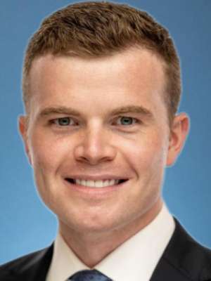 Smiling man in suit and tie against blue studio backdrop