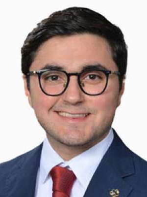 Elisarraras Francisco, smiling headshot in suit, glasses, red tie.