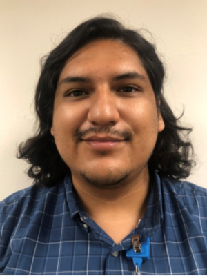 Kevin Pizarro with shoulder length black hair wearing a blue and white checkered shirt