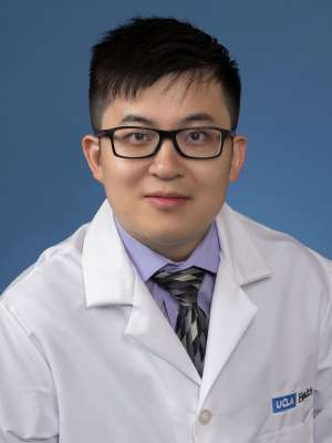 Head shot of Yuxing Xia in white lab coat, looking at camera