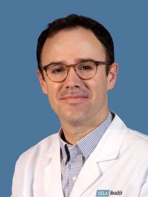 Headshot of Samuel Good, MD, wearing a white coat against a blue background.