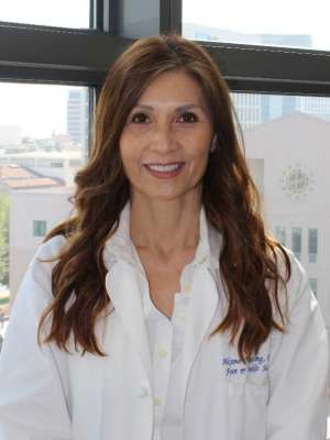 Portrait of Aksone Nouvong, DPM, in a white coat with a blurred face.