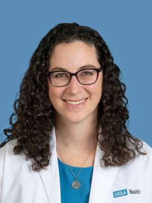 Ashley F. Stein-Merlob, MD wearing a white coat and glasses, smiling