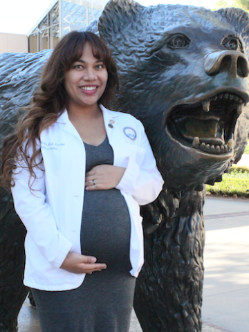Ann Fortes posing 38 weeks pregnant in front of a copper statue of a bear