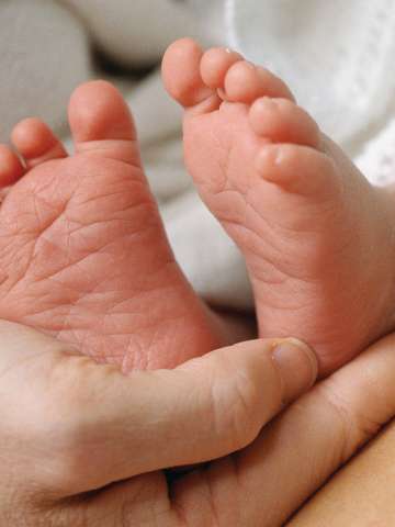Adult hand holding baby feet