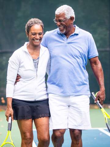 A senior couple together on the tennis court.