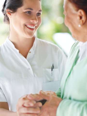 Female nurse comforting older female patient
