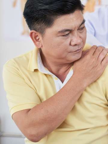 Senior Asian man visiting doctor as he is suffering from pain in shoulder.