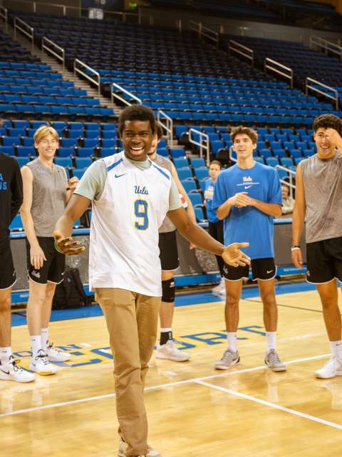 A patient is honored by the UCLA men's volleyball team on the court.