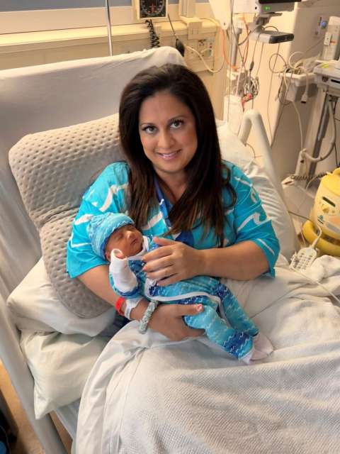 A new mom in a hospital bed holds her baby.