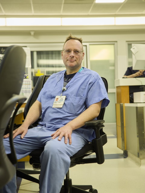 A doctor in scrubs sits at a desk in the hospital.