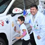 Dr. Steven Jonas and a patient at UCLA Mattel Children's Hospital put their handprints on a Hyundai during a celebration of Dr. Jonas receiving a $400,000 research grant.