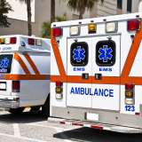 Two ambulances parked, showing rear doors with emergency medical symbols.