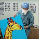 Dr. Zhuang T. Fang shows a medicine cap mosaic created by nurses Cody Kaufman and Joanna Franco-Perez. (Photo by Joshua Sudock/UCLA Health)