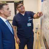 Clinical Nurse Abraham Urias, right, presents his fall prevention project poster to Chief Nursing Officer Patrick Loney in the 4 East Adult Psychiatric unit.