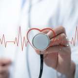 Medical worker holding stethoscope pointing heart wave Red line wave of heart beat. 